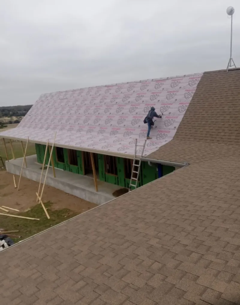 Worker preparing underlayment for a metal roof installation in Monrovia